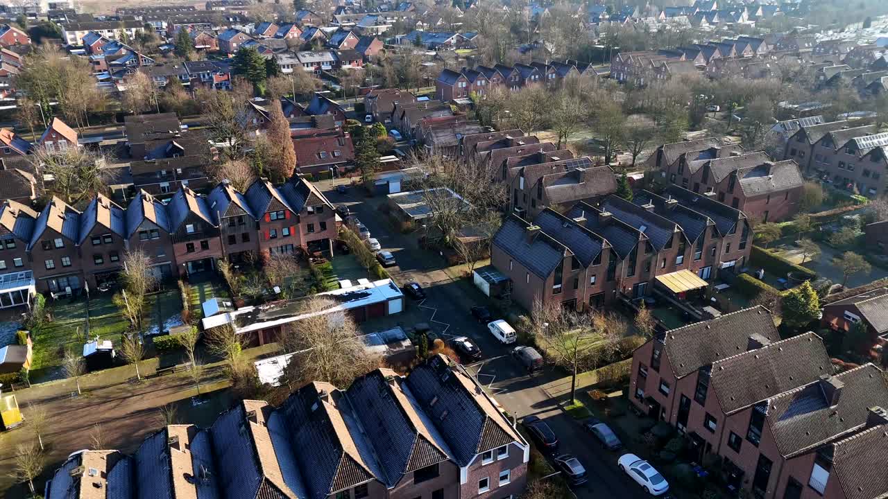 Aerial flyover townhouses in suburb neighborhood during cold sunrise in winter season. Top down shot. Formation of houses in row.