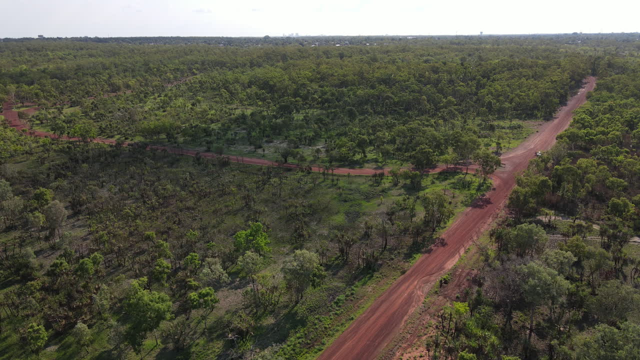 Pomalý záběr dronem na Červenou silnici a zelenou buš poblíž přírodního parku Holmes Jungle, Darwin, Severní teritorium.