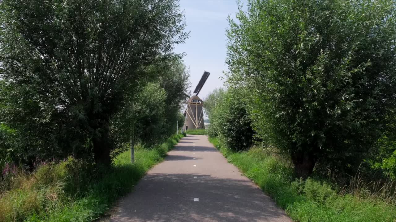 Scenic Bike Path Leading to a Windmill in the Netherlands