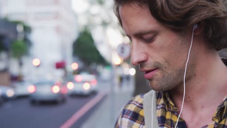 caucasian male putting on earphones on a bike in a street