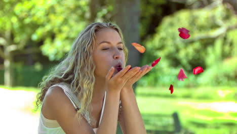 blonde woman in slow motion blowing on petals