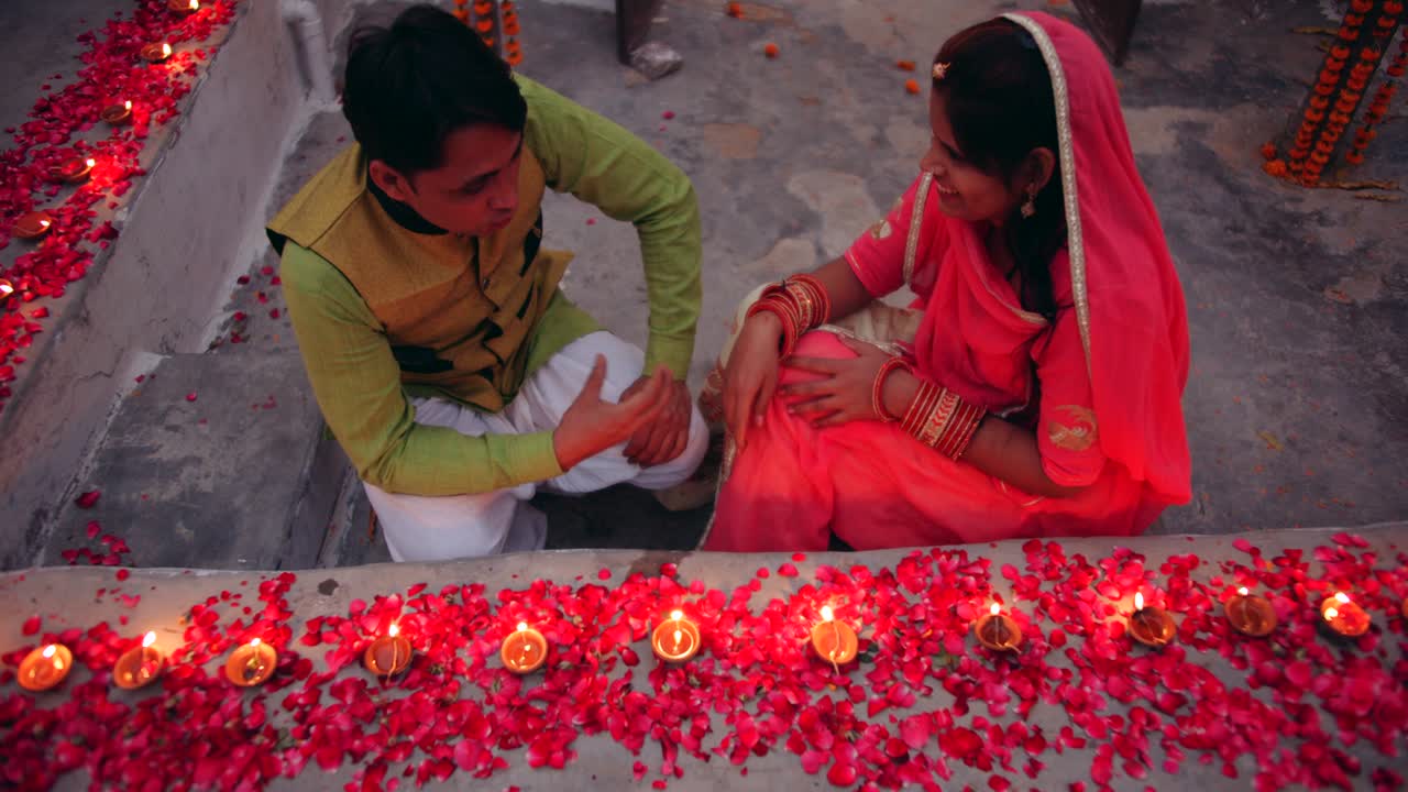Par fejrer en farverig Diwali rangoli - rød, pink, orange, grøn