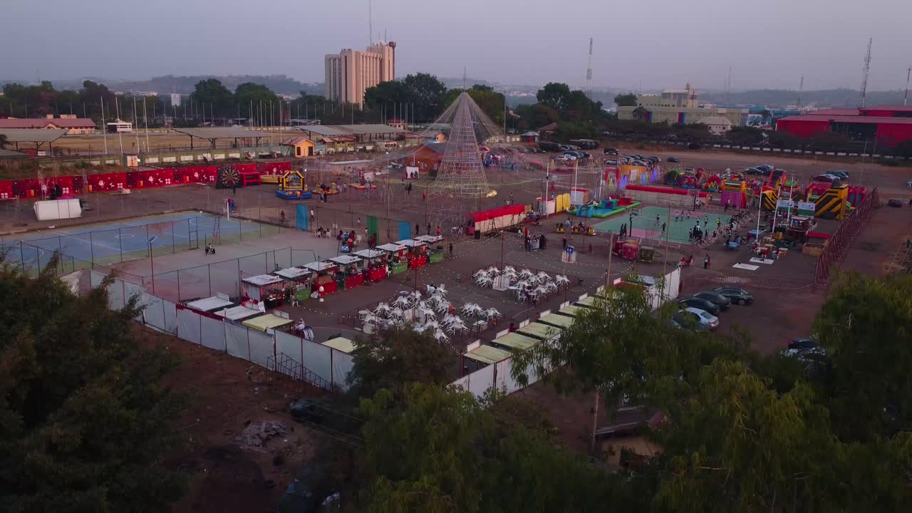 Ripresa dall'alto di un colorato carnevale all'Old Parade Ground al crepuscolo ad Abuja, in Nigeria. Riprese aeree che catturano le numerose attività divertenti della festosa fiera di contea.