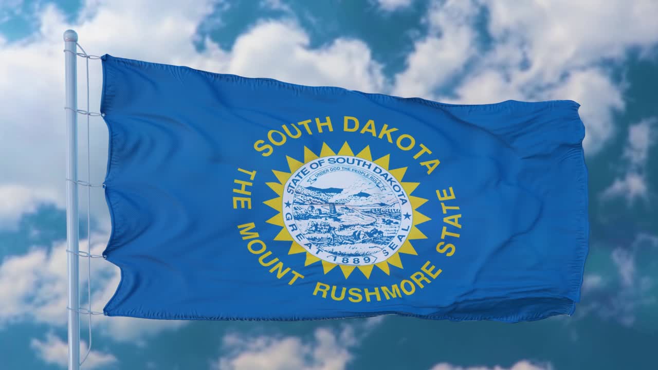 South Dakota flag on a flagpole waving in the wind, blue sky background