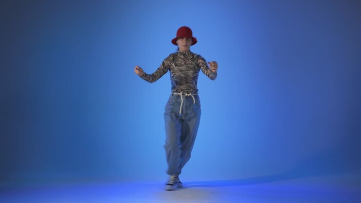 Young woman dancing house, energy jumps on blue background, studio shot