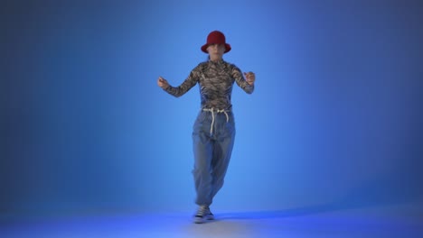 mujer joven bailando en la casa, energía salta sobre fondo azul, toma de estudio
