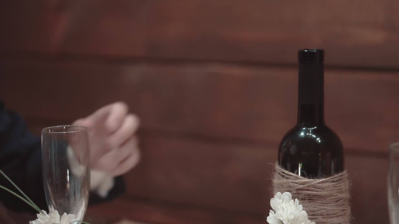 Young man takes a bottle of wine from a table close-up slow motion