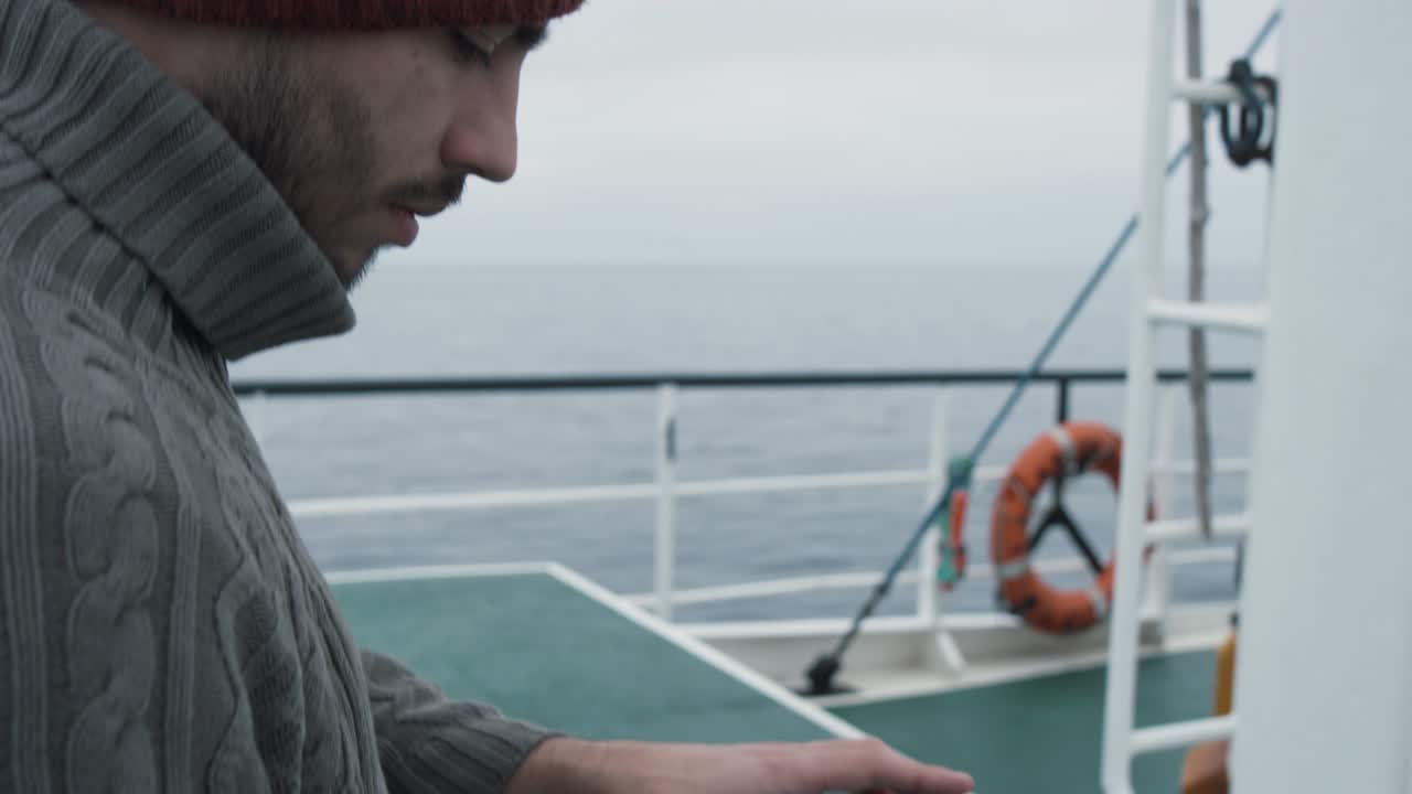 보호 코트를 입은 시이 배를 타고 여행하는 동안 내비게이션 지도와 함께 태블릿 컴퓨터를 사용합니다.