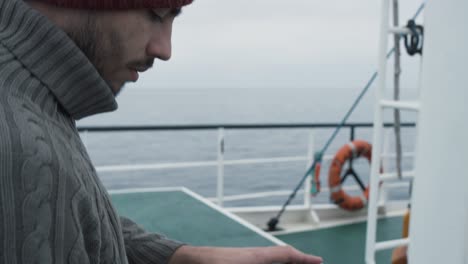 dressed in protective coat fisherman using tablet computer with navigation maps while traveling on ship.