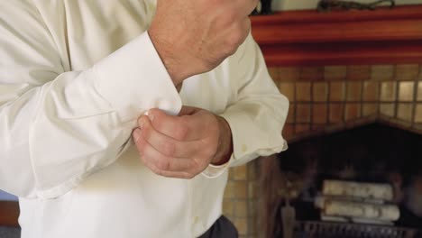 caucasian man slowly buttons white dress shirt sleeve cuff