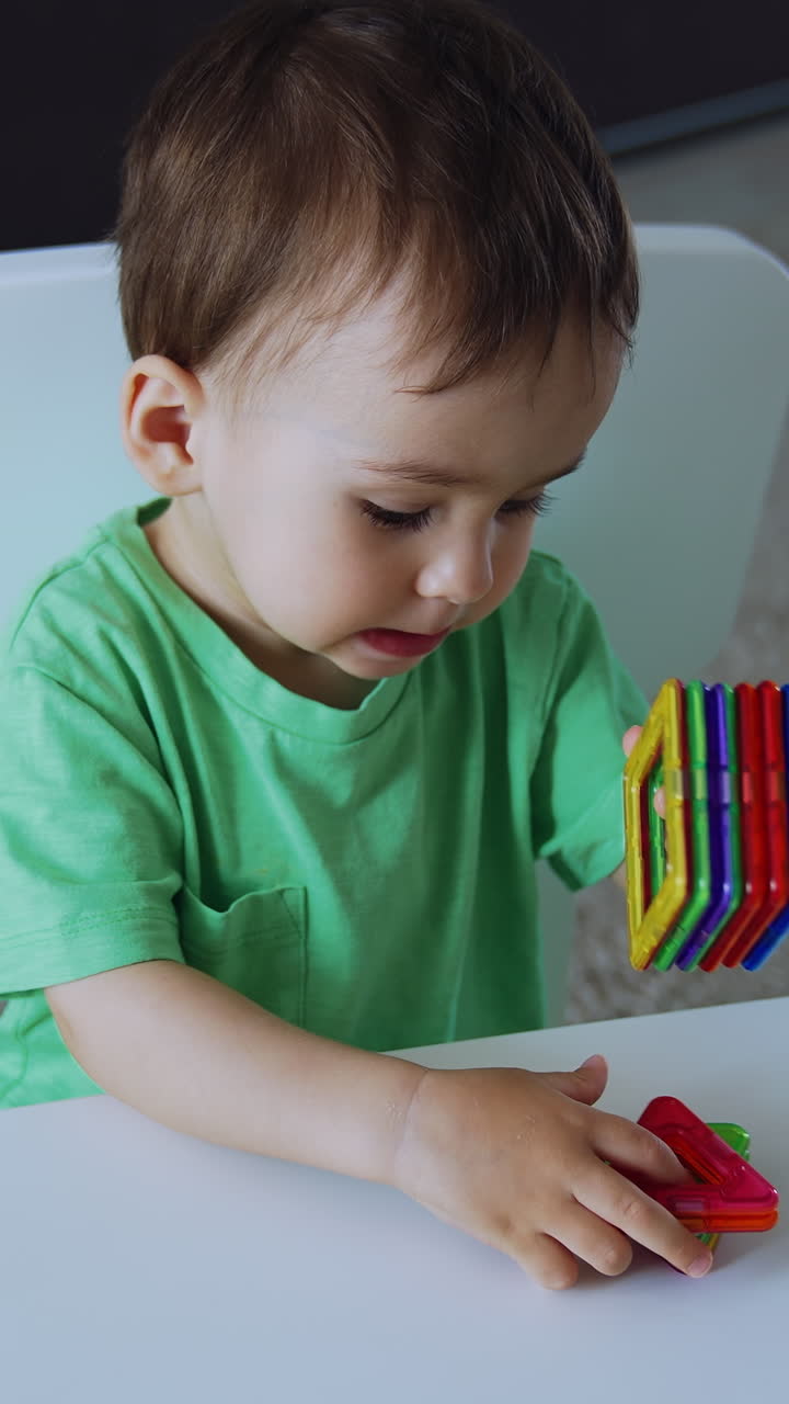 Little boy plays with toys of different geometrical shape. Adorable toddler is talking while playing. Top view. Vertical video