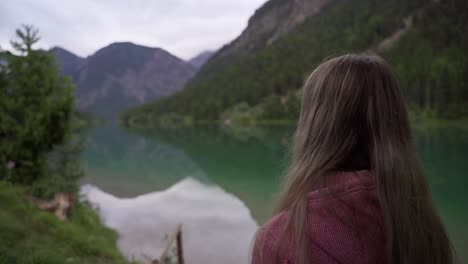 una chica rubia se queda frente a un bonito lago