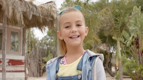 portrait of happy caucasian girl looking at camera over palm trees