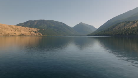 antena moviéndose horizontalmente sobre el pintoresco lago alpino con montañas detrás