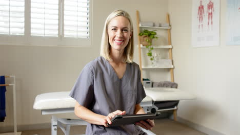 smiling female technician in prosthetic lab holding digital tablet, ready to assist