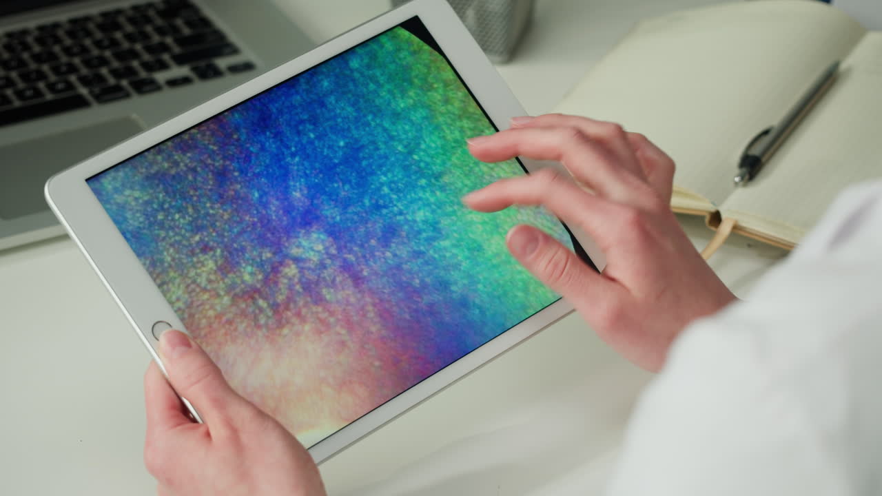 Woman using a tablet with colorful display on desk.