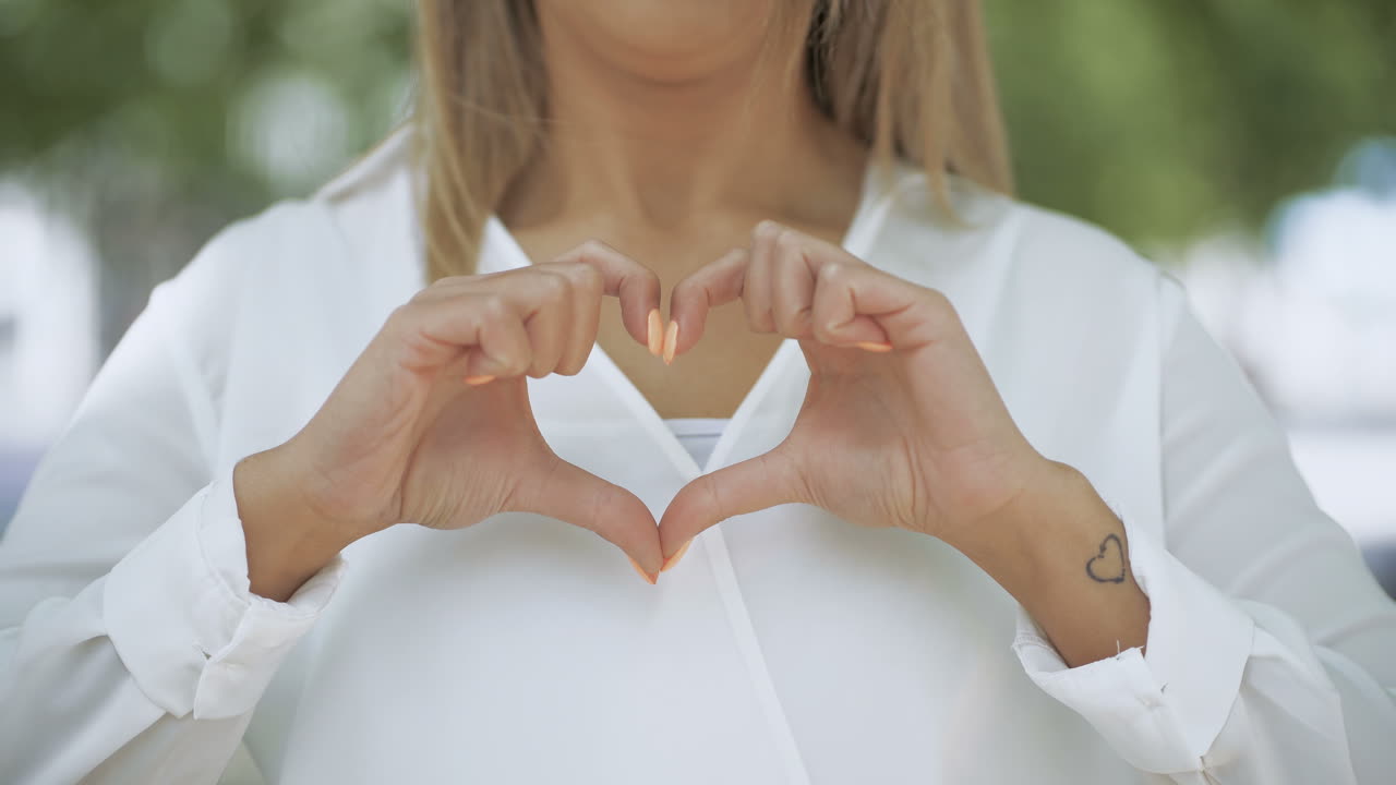 fotografía recortada de una niña mostrando el corazón de la mano