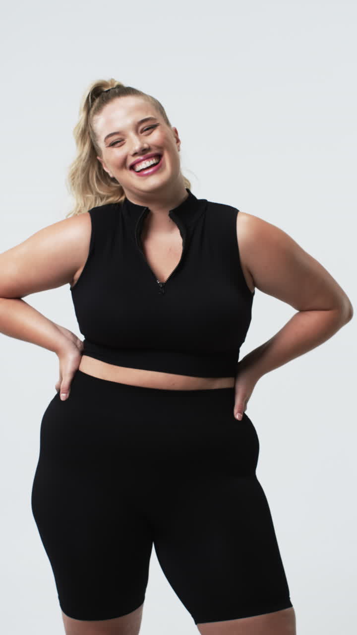 Video verticale: Donna curvy sorridente in abbigliamento sportivo che posa con sicurezza, promuovendo la body positivity.