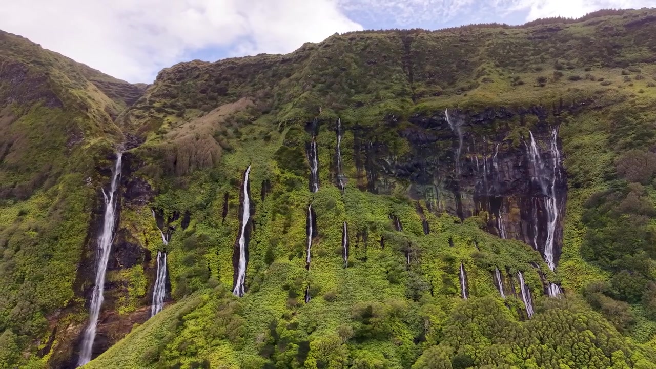 Veduta panoramica cinematografica di cascate che scendono attraverso un vibrante paesaggio vulcanico a Poco da Ribeira do Ferreiro nelle Azzorre, Portogallo.