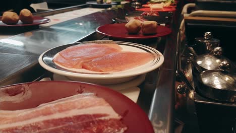 row of japanese food buffet dishes on belt. conveyor of japanese food belt for hot pot or shabushabu.