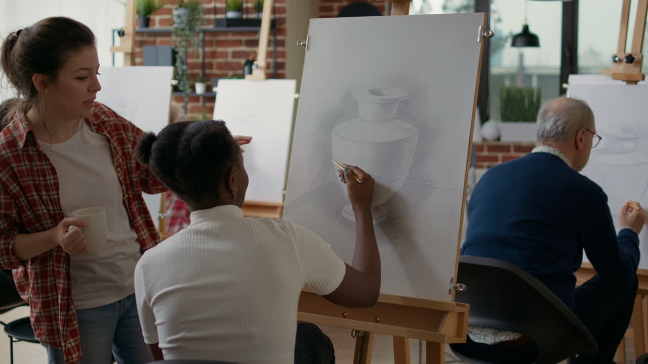 Teacher explaining to young woman how to draw vase model