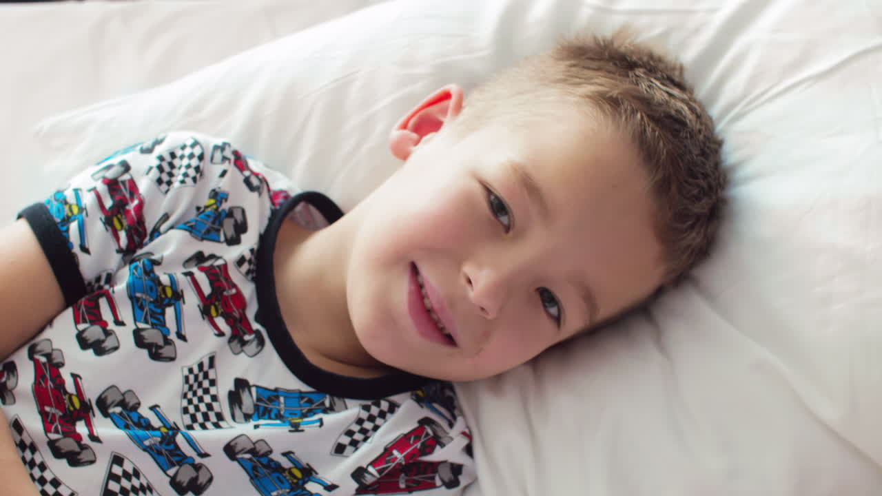 여섯 달 된 아기 소녀와 일곱 살 된 소년 형제 자매는 집에서 침대에 있습니다.