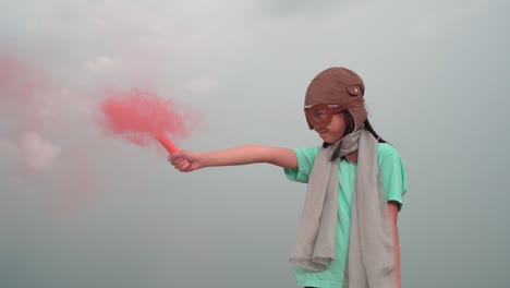 young girl with pilot goggles and hat, asian kid playing at outdoor with color smoke