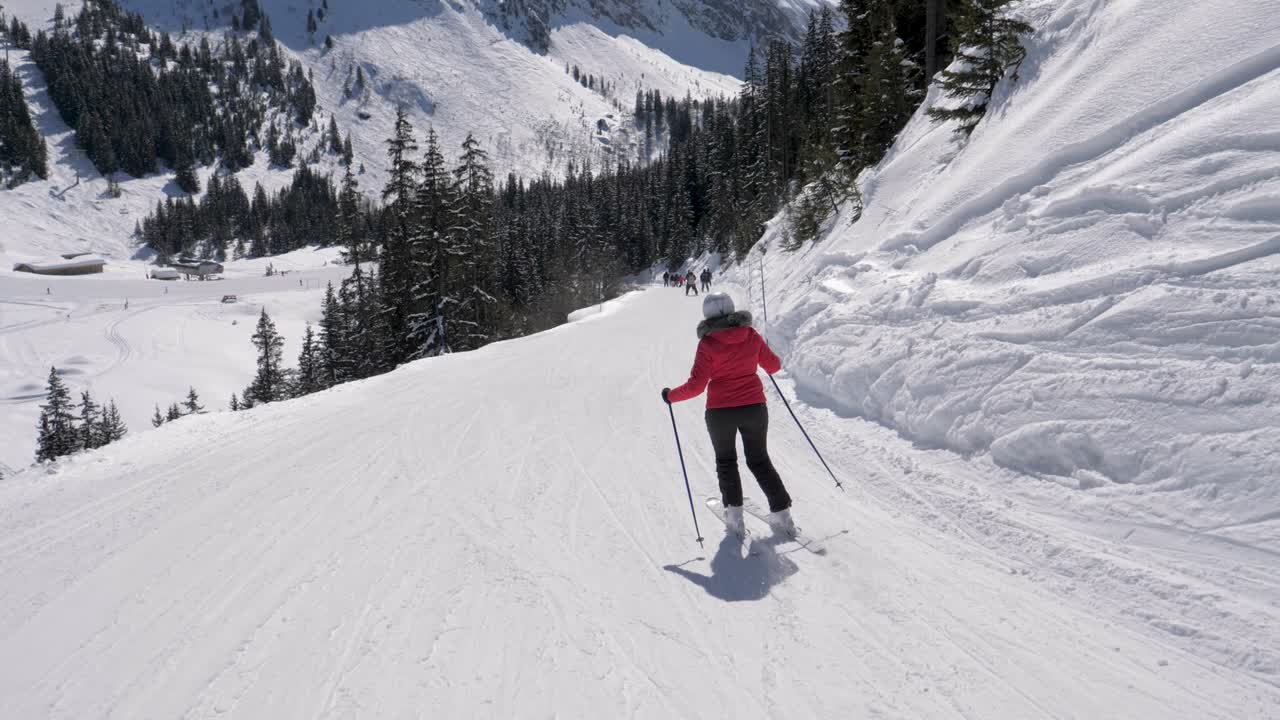 Sciatore maturo che scia in discesa sul fianco della montagna in inverno