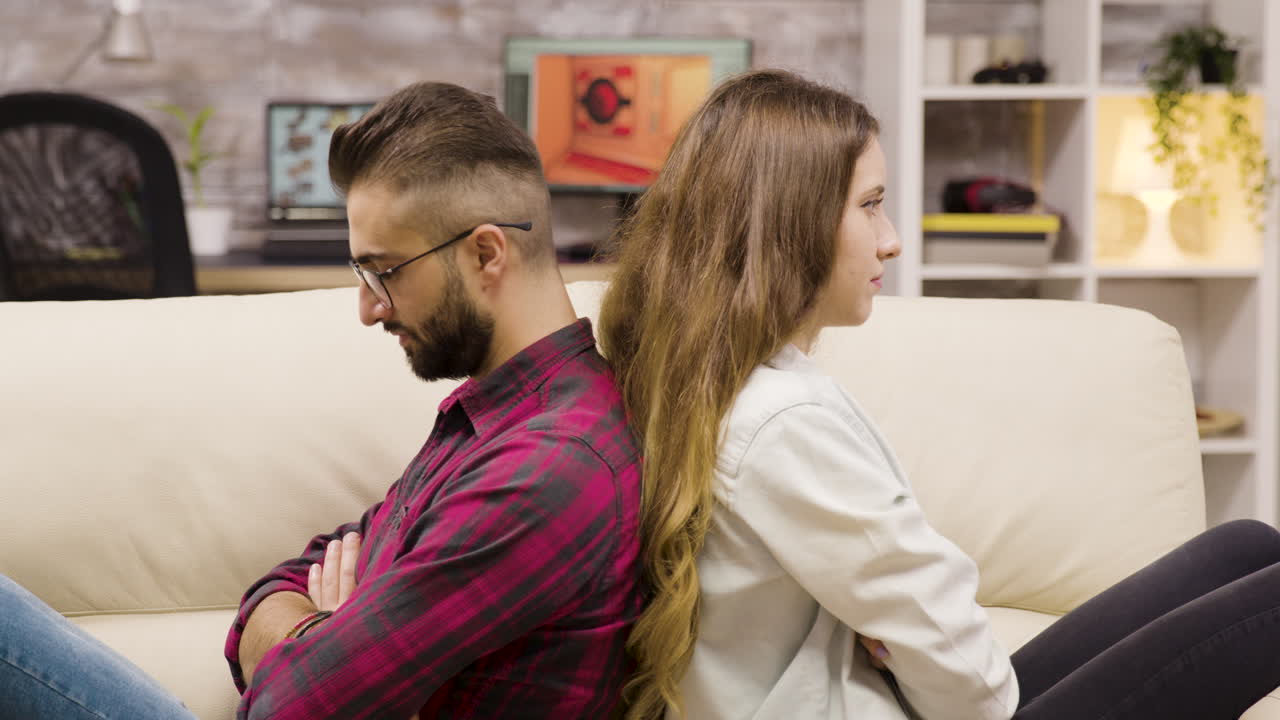 Couple sitting back to back on a couch, symbolizing relationship conflict