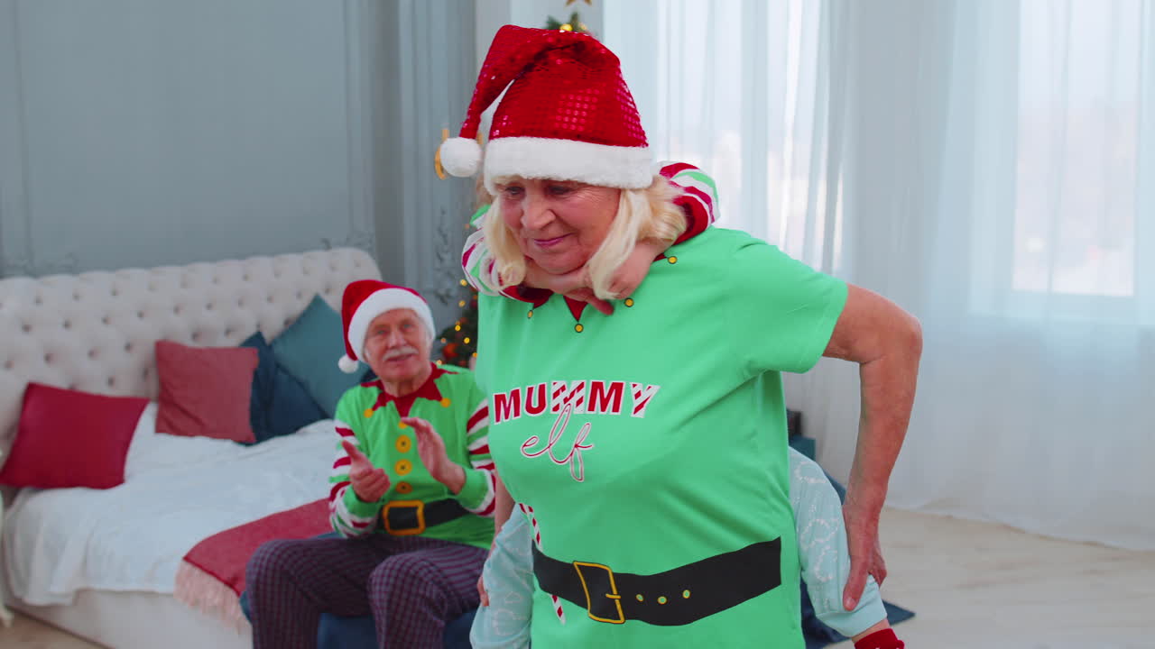 abuela llevando una niña pequeña niño pequeño, jugando al juego de paseo en la espalda en el dormitorio de navidad