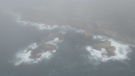 dense sea fog covered the rocky shore with breaking waves in tamarama beach, sydney, australia