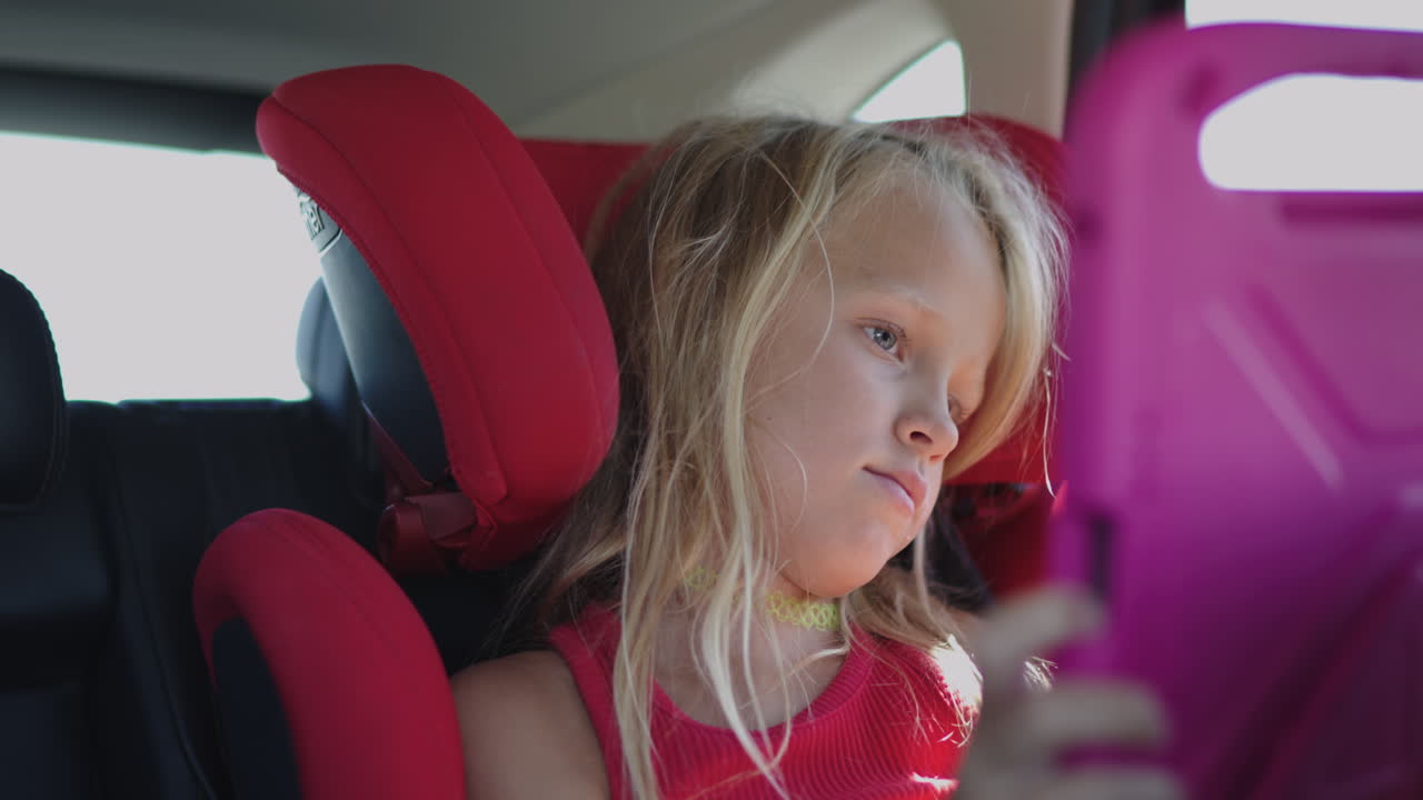 Child in car seat watching tablet