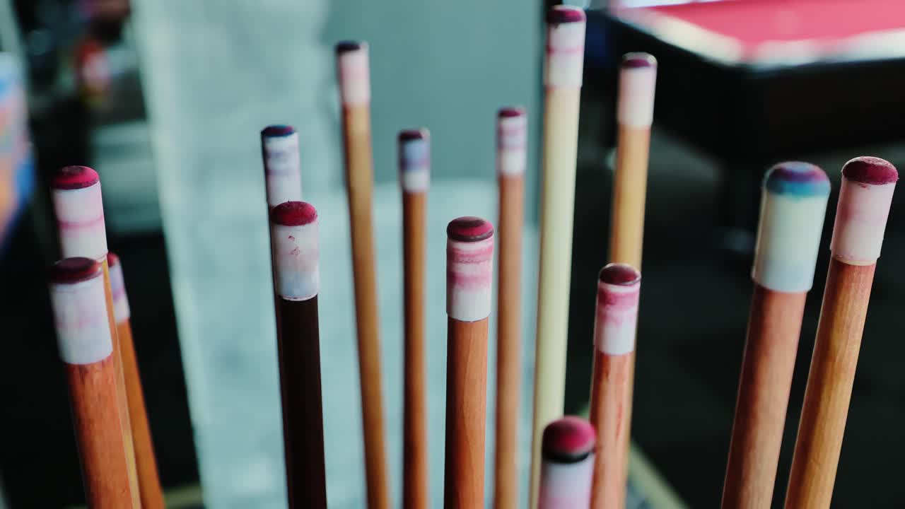 Close-up shows worn cue tips coated in chalk beside billiards table