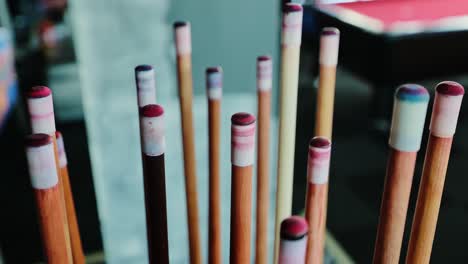 close-up shows worn cue tips coated in chalk beside billiards table