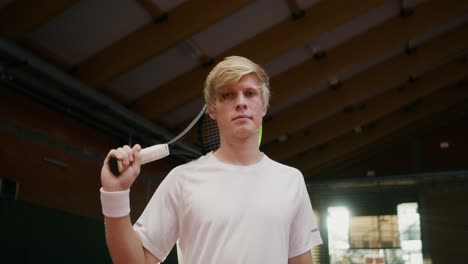 young man holding tennis racket on indoor tennis court