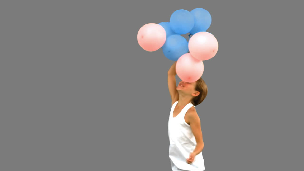 회색 스크린에서 풍선으로 놀고 있는 어린 소녀