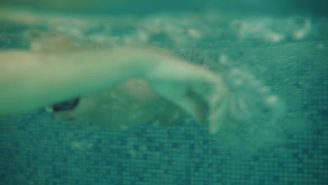 a little boy is jumping from the side of the pool into the water. mom waits for him in the water. the boy dives under the water in swimming glasse, rowing under the water. mother catch him and smiling
