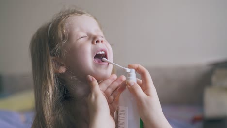 Una-Mujer-Rocía-El-Dolor-De-Garganta-De-Una-Niña-Enferma-Con-Un-Remedio-En-Casa