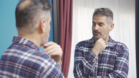 thoughtful and unhappy mature man suffering from grief and loneliness at home.