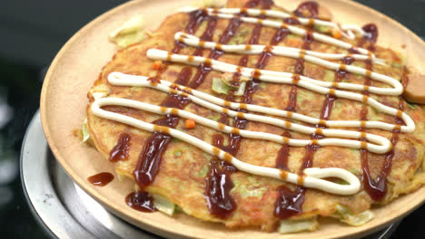 putting sauce on okonomiyaki or japanese pizza