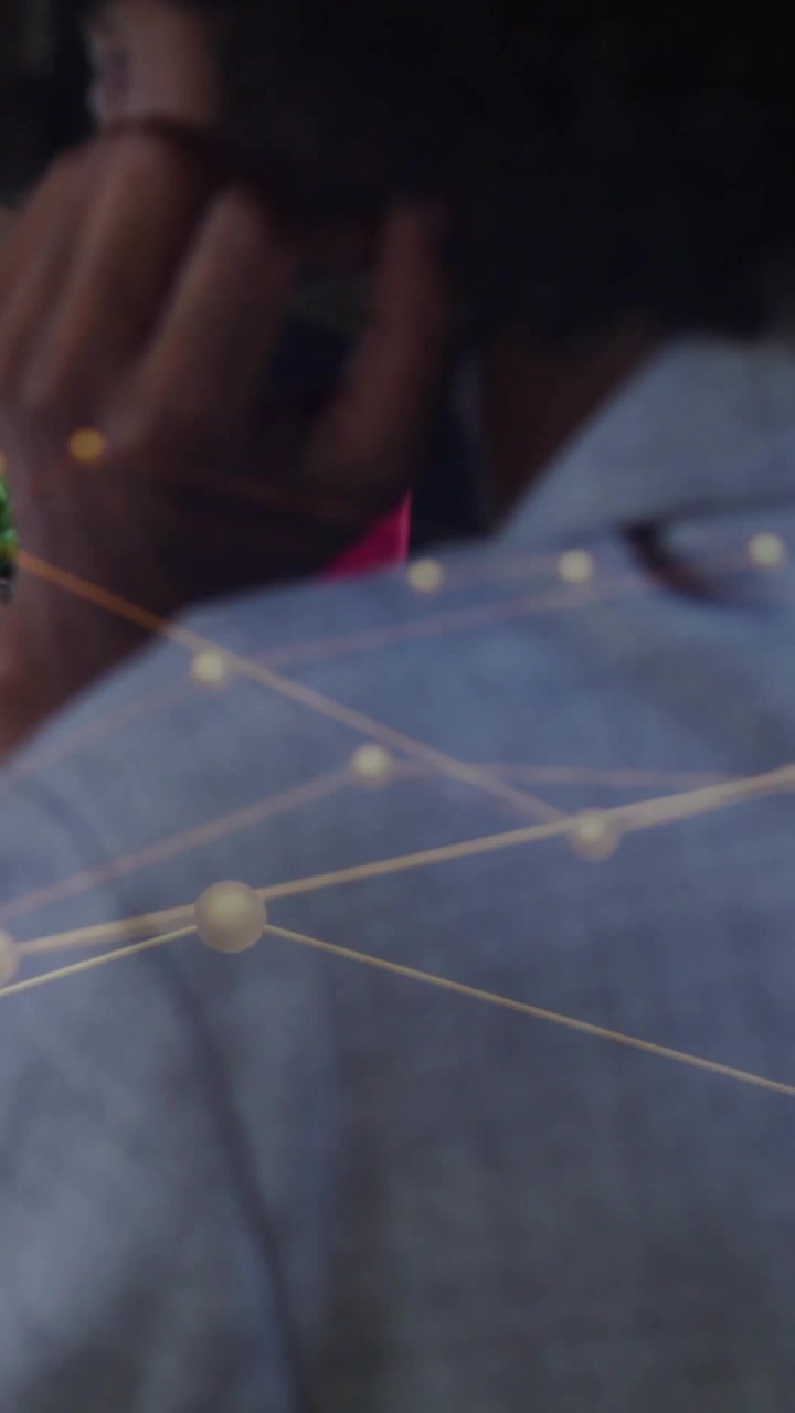 Vertical video: Woman taking call turning right golden nodes over her profile showing desk for tech