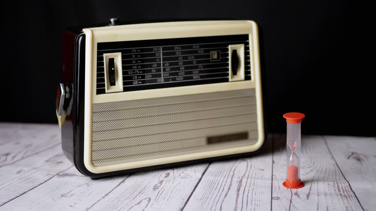 오래된 빈티지 리시버가 테이블 위에 서서 모래시계를 가지고 시간을 카운트다운하고 있습니다.
