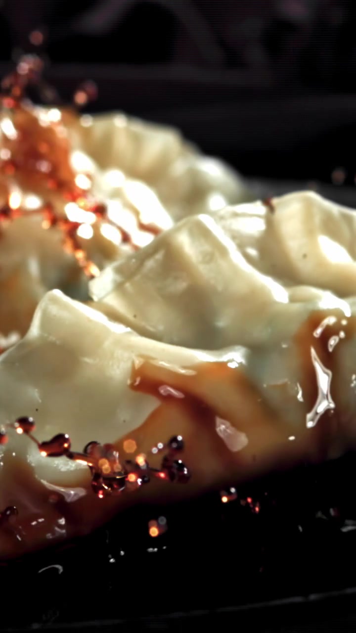 Slow Motion Close-up of Soy Sauce Being Poured Over Dumplings