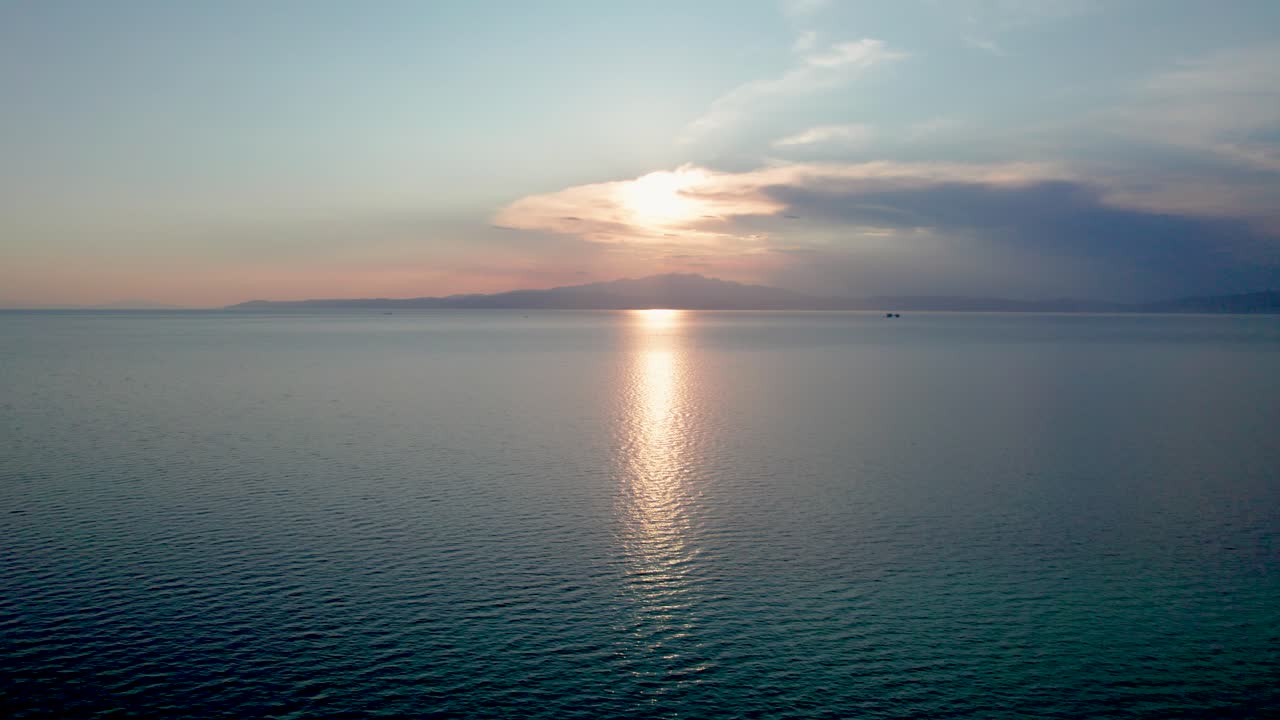 toma cinematográfica de la playa de prinos al atardecer, movimiento hacia abajo, cordillera en el fondo, cielo naranja, isla de thassos, grecia, europa