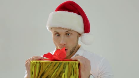 surprised man in santa hat opening a christmas gift