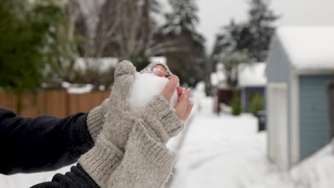 close up of person with gloves forming a snowball and throwing away during cold winter day in residential area