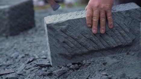 Handheld-shot-of-a-cancagua-stone-craftsman,-shaping-stone-slabs-with-hand-tools-in-the-city-of-Ancud,-Chiloe-Island