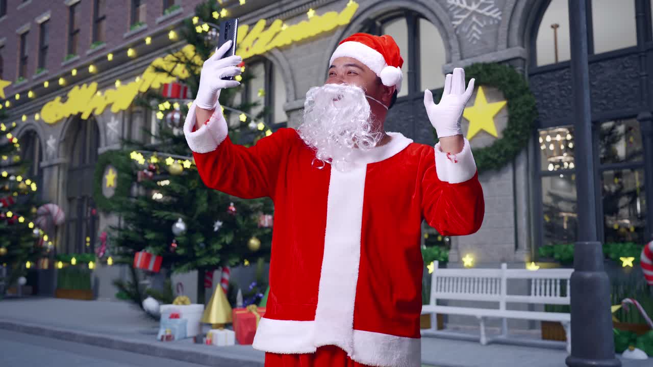 아시아 산타클로스가 크리스마스 밤에 스마트폰으로 누군가와 비디오 컨퍼런스 통화를 하고 있습니다.