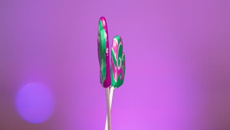 mezcla de piruletas en espiral girando sobre un fondo rosado. caramelo caramelo en un palo en forma de corazón