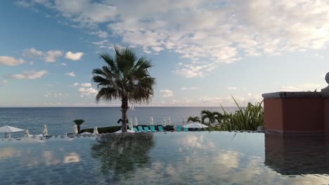 Vista-Idílica-Sobre-El-Horizonte-Del-Océano-Y-Barcos-Desde-La-Piscina-Infinita-Del-Hotel-De-Lujo-Con-Reflejo-De-Espejo-En-La-Superficie-Del-Agua